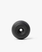 The HMM Paperweight Pen Stand (Black) is a circular aluminum piece with concentric raised rings and a central hole, shown on a plain white background.