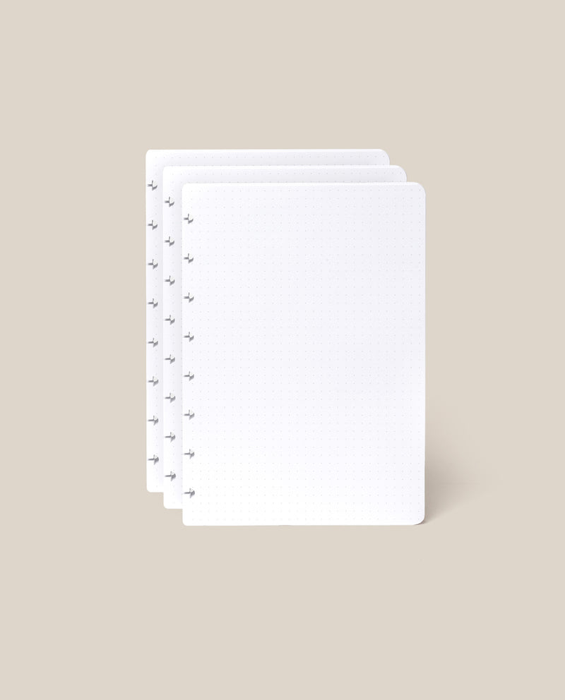 Three stacked sheets from the Discbound Journal Refill (Standard 6" x 8.5" – 3-Pack), featuring a white dot grid and circular holes along the left edge, displayed on a light beige background—ideal for discbound notebooks.