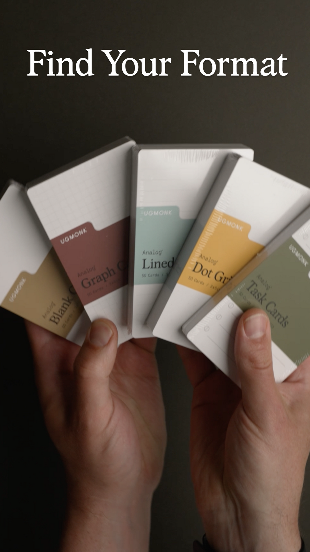 Two hands hold five different Ugmonk notepads fanned out, each featuring a distinct label. Text above reads, Find Your Format.