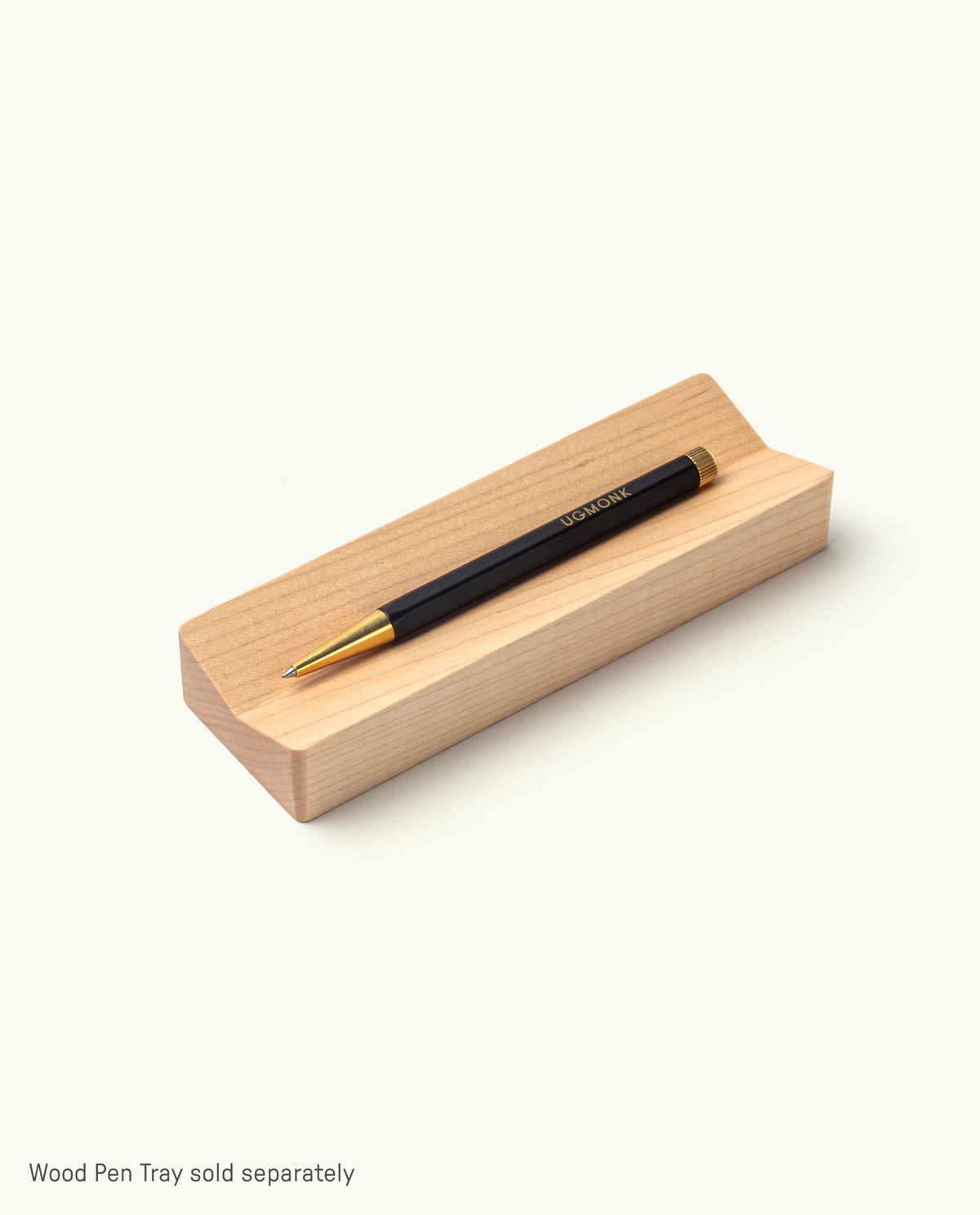 The Ugmonk Pen (Leuchtturm1917 Drehgriffel - Black) sits on a light wooden pen tray against a plain white background. Text below says, “Wood Pen Tray sold separately.”.