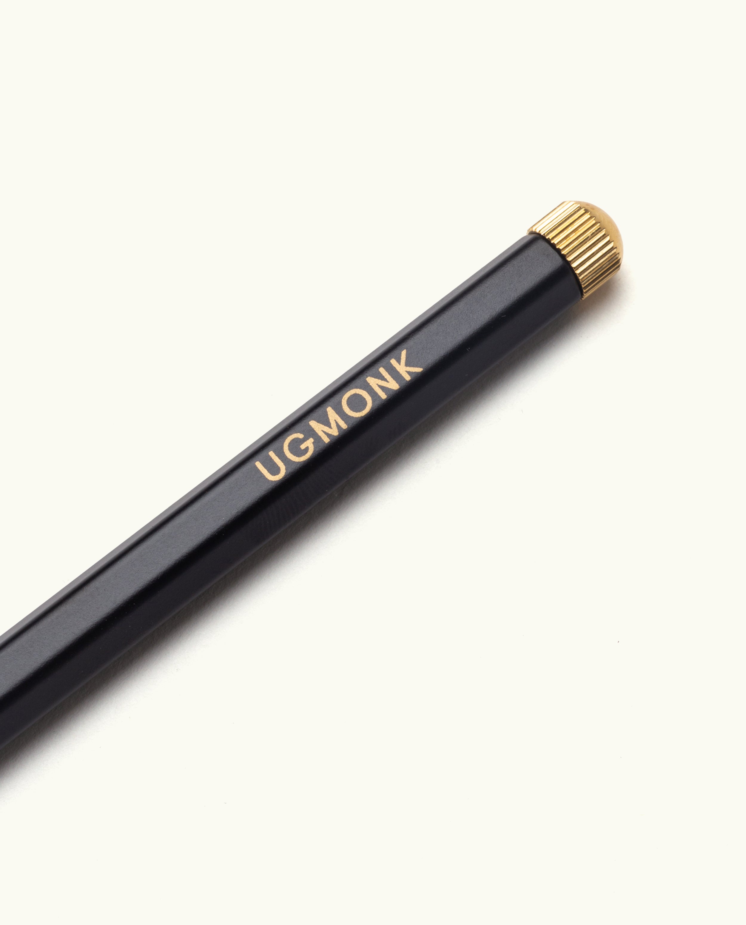 The Ugmonk Pen (Leuchtturm1917 Drehgriffel - Black) features a black body, metallic gold eraser cap, and "UGMONK" printed in gold on the side, shown against a light background.