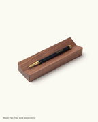 A black Ugmonk Pen (Leuchtturm1917 Drehgriffel) sits on a rectangular wooden pen tray against a plain white background. The bottom left corner notes the pen tray is sold separately.