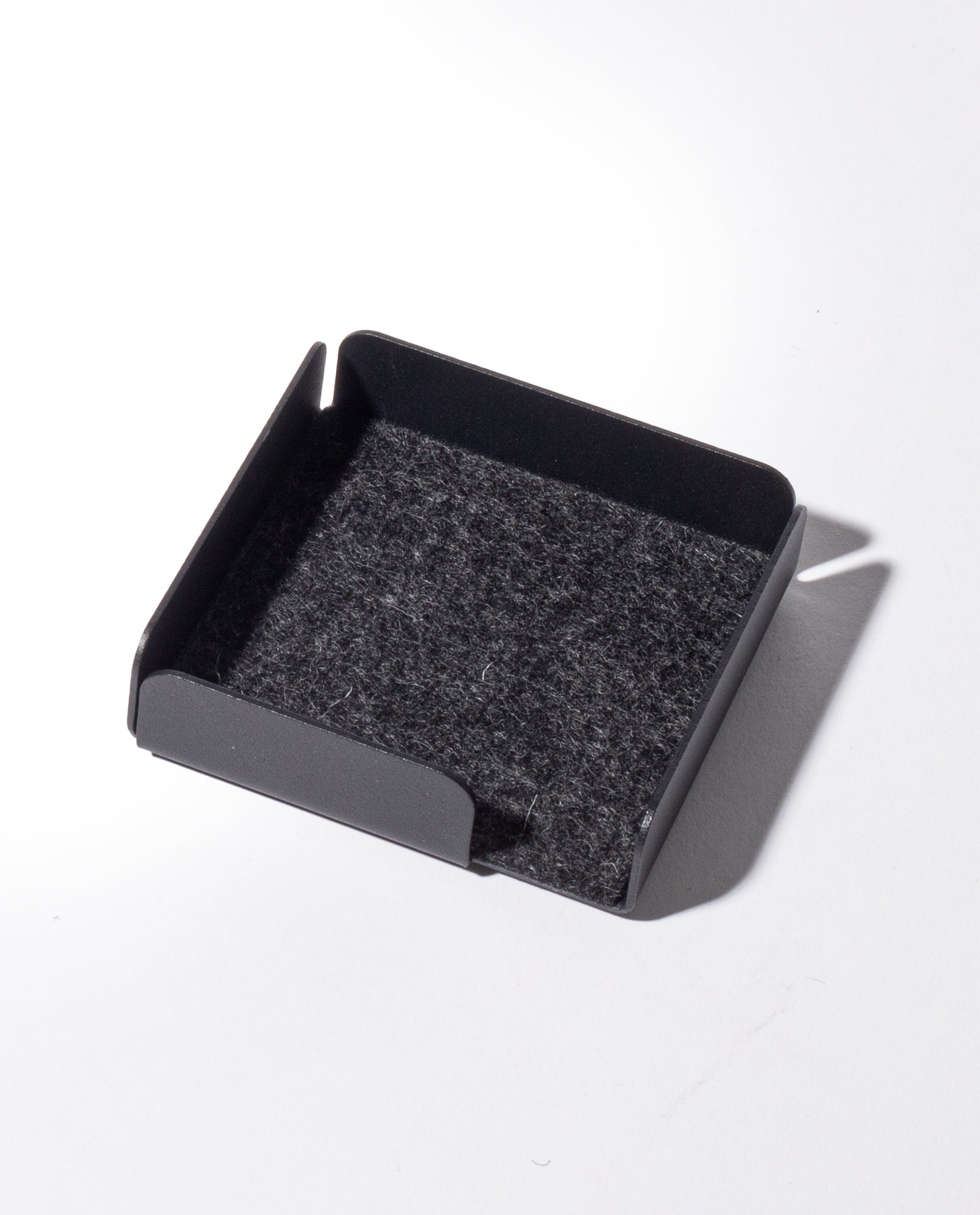 The Gather Note Tray (1x1 - Black) is a black, square-shaped magnetic desk organizer featuring low sides and a felt-lined bottom, photographed on a white background with a shadow falling to the right. Proudly made in the USA.