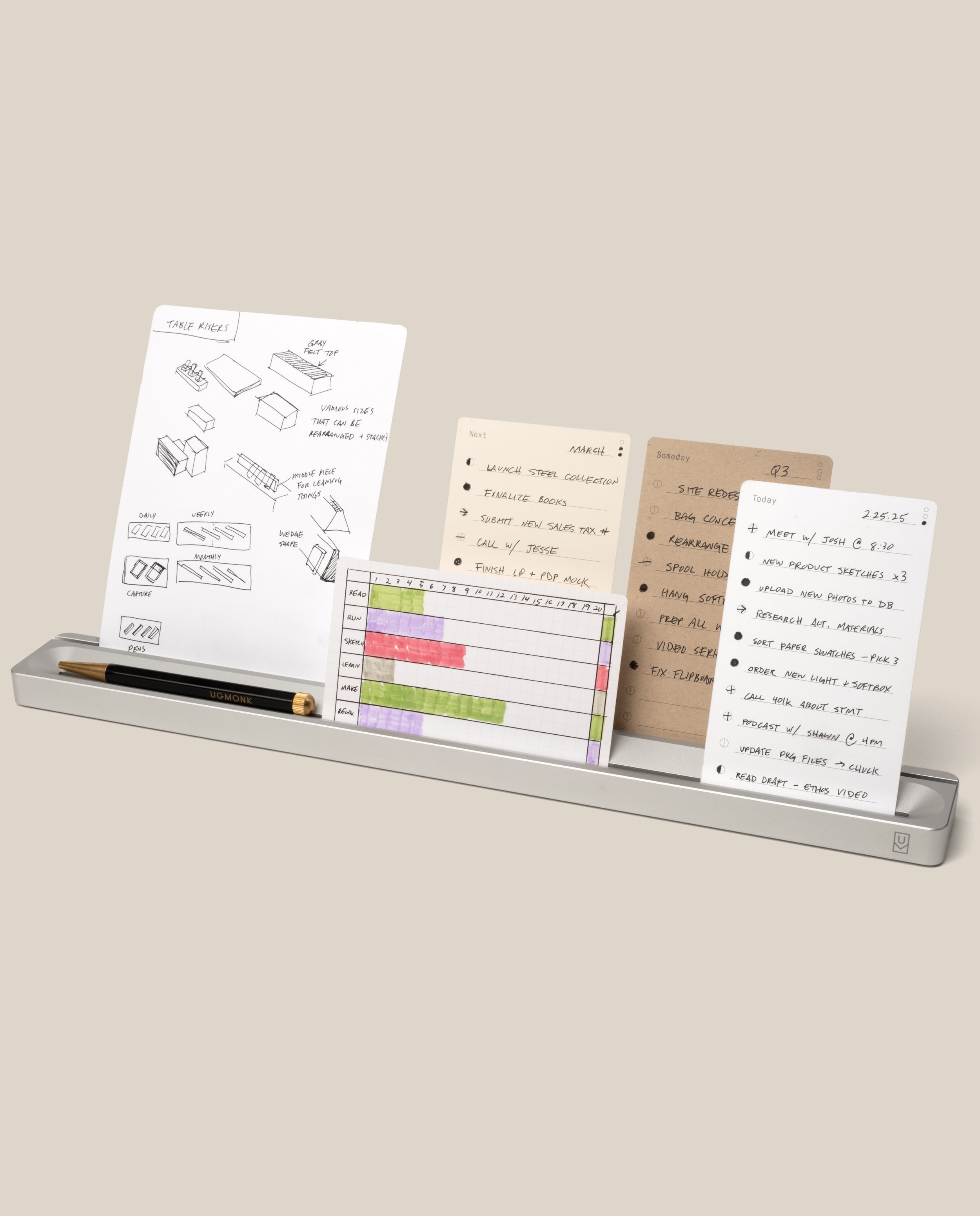 The Complete Analog Collection (Silver Aluminum) serves as a stylish metal desk organizer, neatly holding pens and four note cards—one displaying sketches, another listing a checklist, a third featuring a colored chart, and the fourth showing handwritten notes—all presented upright against a neutral background.