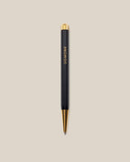 The Ugmonk Pen (Leuchtturm1917 Drehgriffel - Black) features gold accents and "UGMONK" printed vertically on its barrel, shown against a light beige background.