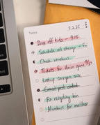A set of Analog Task Cards - Small, featuring handwritten tasks like dropping off kids and scheduling an oil change—some checked off or crossed out in various colors—lies beside a laptop, exemplifying a straightforward analog system in use.