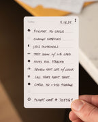 A hand displays an Analog Task Cards - Small to-do list, featuring photography tasks dated 4.13.25—such as formatting SD cards, charging batteries, reviewing the shot list, and noting flight case number 708994—an excellent analog system for staying organized.