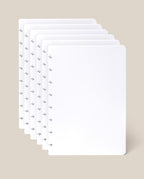 Five sheets of the Discbound Journal Refill - Blank (Standard 6″ x 8.5″), each crisp and white with rounded corners and a row of small arrow-shaped holes along the left edge—ideal for your Heirloom Discbound Journal—are fanned out against a light beige background.