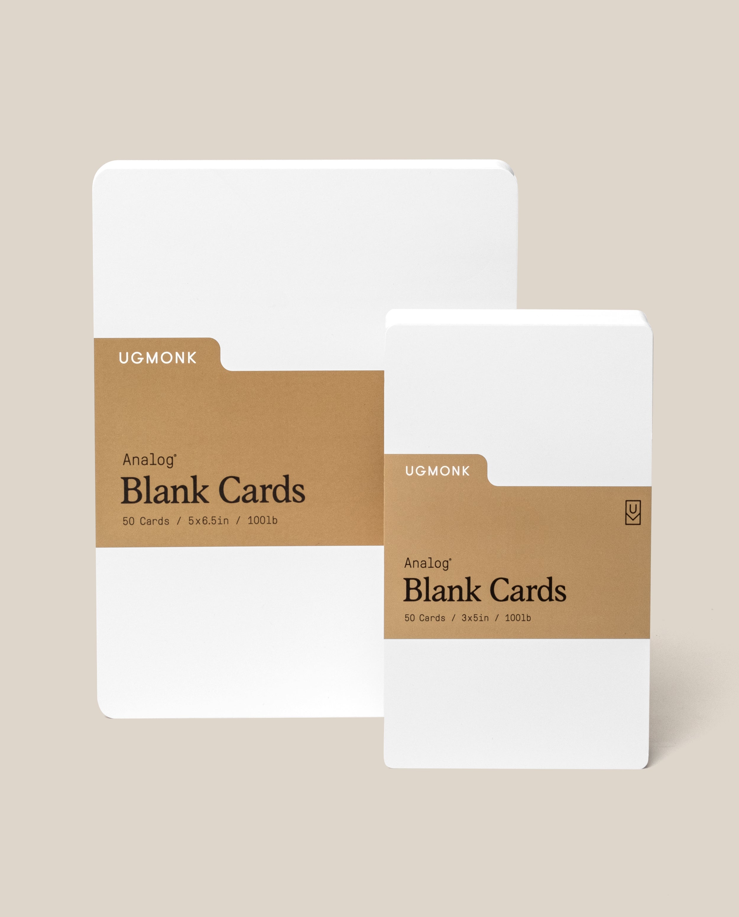 Two packs of Ugmonk Analog Blank Cards, one large and one small, both wrapped in brown paper bands with black text, placed on a beige background.