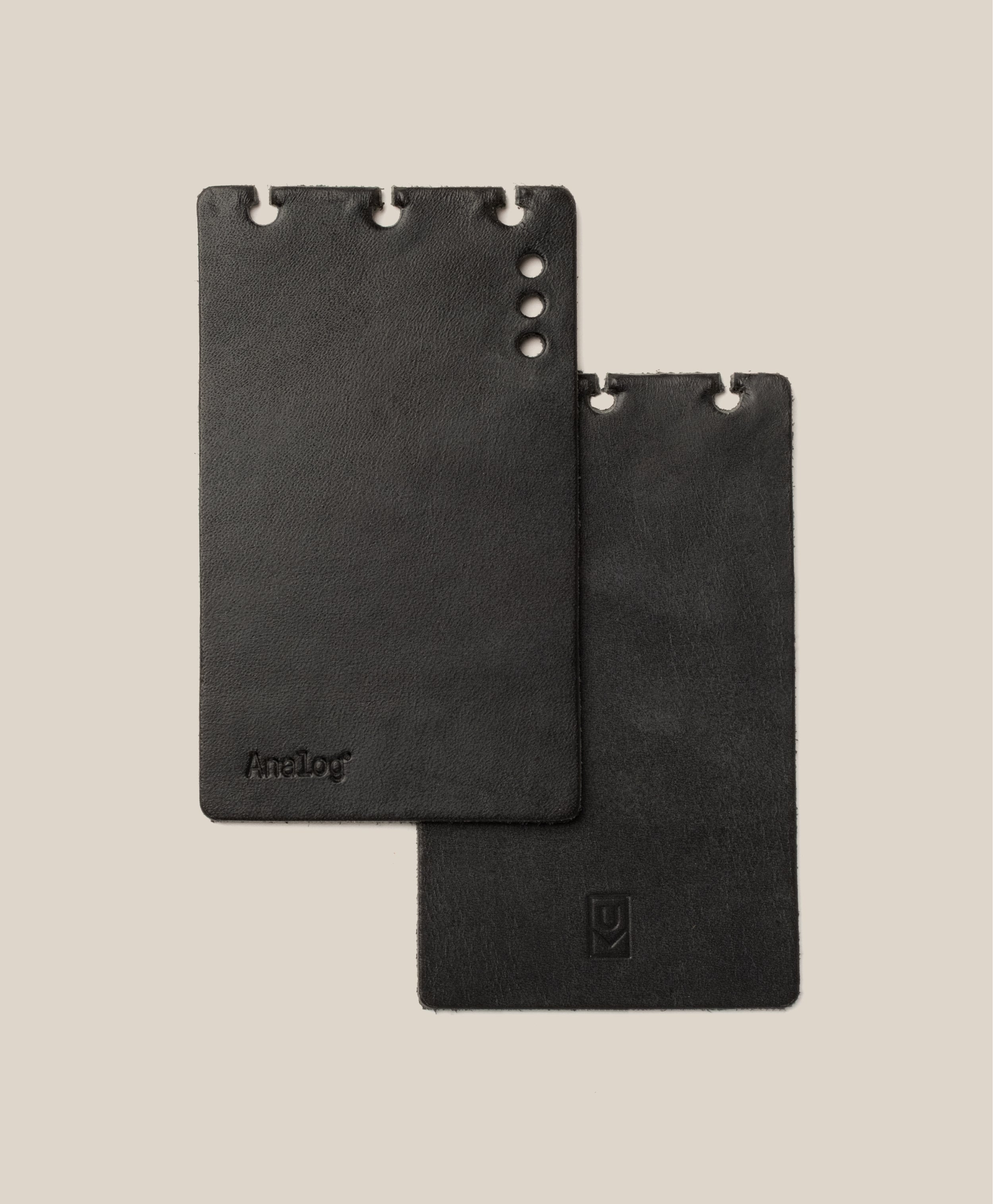 *Covers Only* – Leather Discbound Analog (Black) features two black full-grain leather covers with rounded corners and three holes along the top edge designed for Discbound Analog systems. Each cover displays a subtle embossed logo, and all are made in the USA. The background is a light beige color.