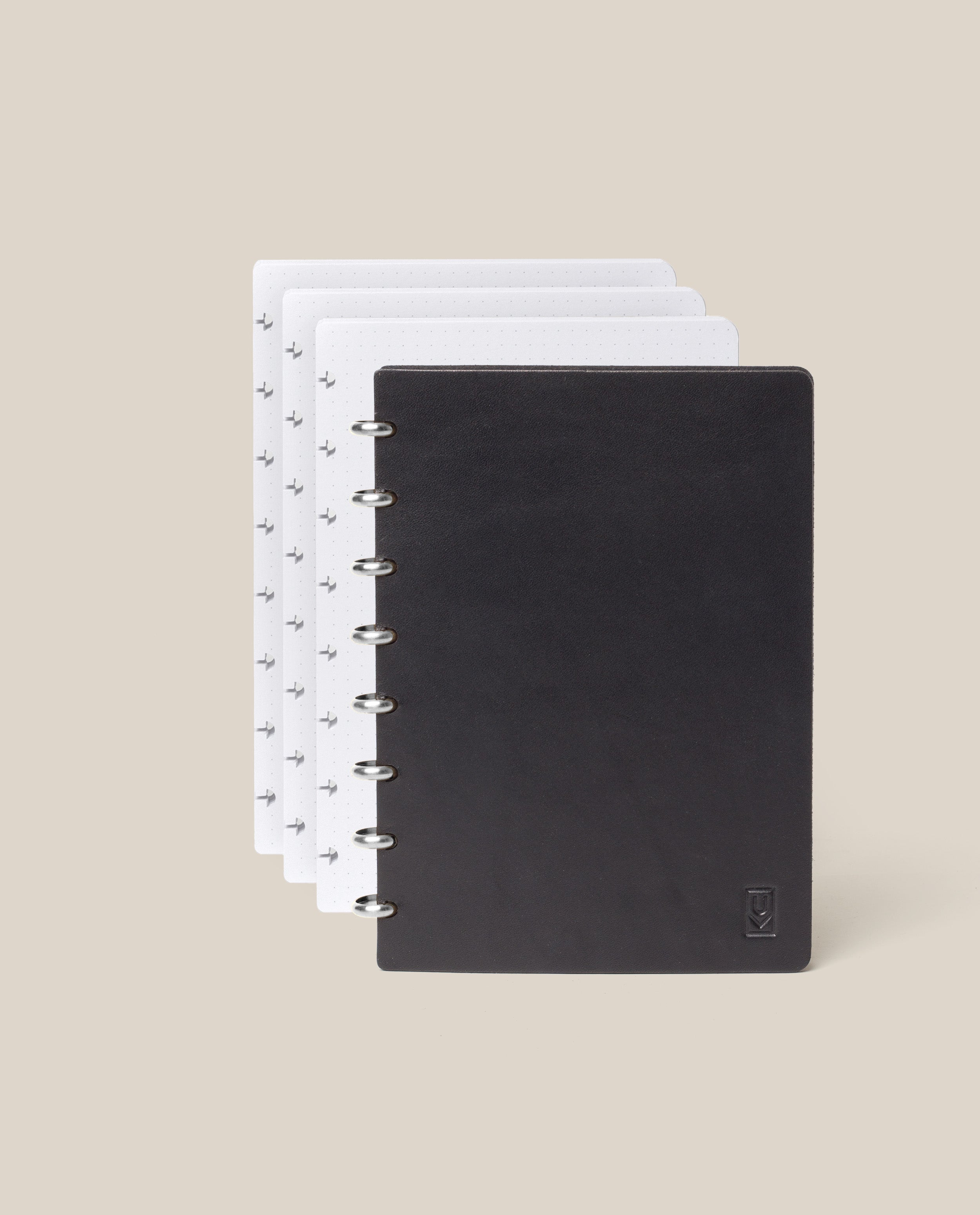 The Discbound Heirloom Journal Bundle in black leather (Standard 6" x 8.5" with 3 refills) is displayed fanned open to show four dotted pages, against a plain beige background.