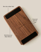 The Analog Daily Focus Kit (Walnut) is a rectangular solid American black walnut card holder with an engraved Ugmonk logo at the center and two black non-slip rubber feet on opposite underside edges.