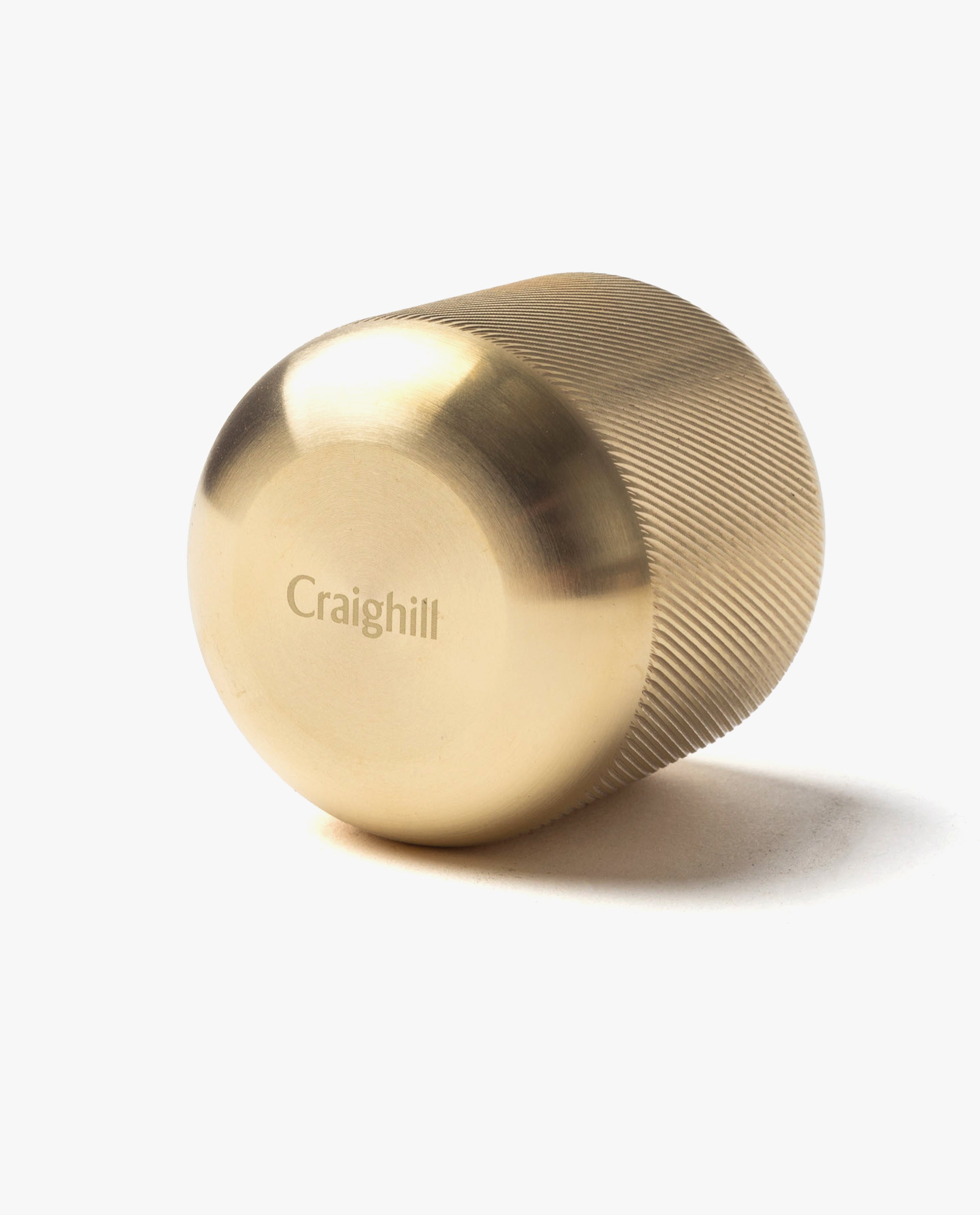 The Craighill Match Striker (Brass) is a gold-colored, cylindrical brass piece with a fine grip and rounded end. "Craighill" is engraved on its side. Designed for strike-anywhere matches, it’s pictured resting on its side against a white background.