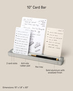 The Warehouse Item - Analog Card Bar (Small 10" - Silver) securely holds up to ten notecards upright. Key features include two card slots, an anti-slip rubber pad, a convenient pen tray (shown with a black pen resting inside), and a sturdy solid aluminum build. Its dimensions are 10" x 1.8" x 0.63". This item is part of our Warehouse Sale Items collection.