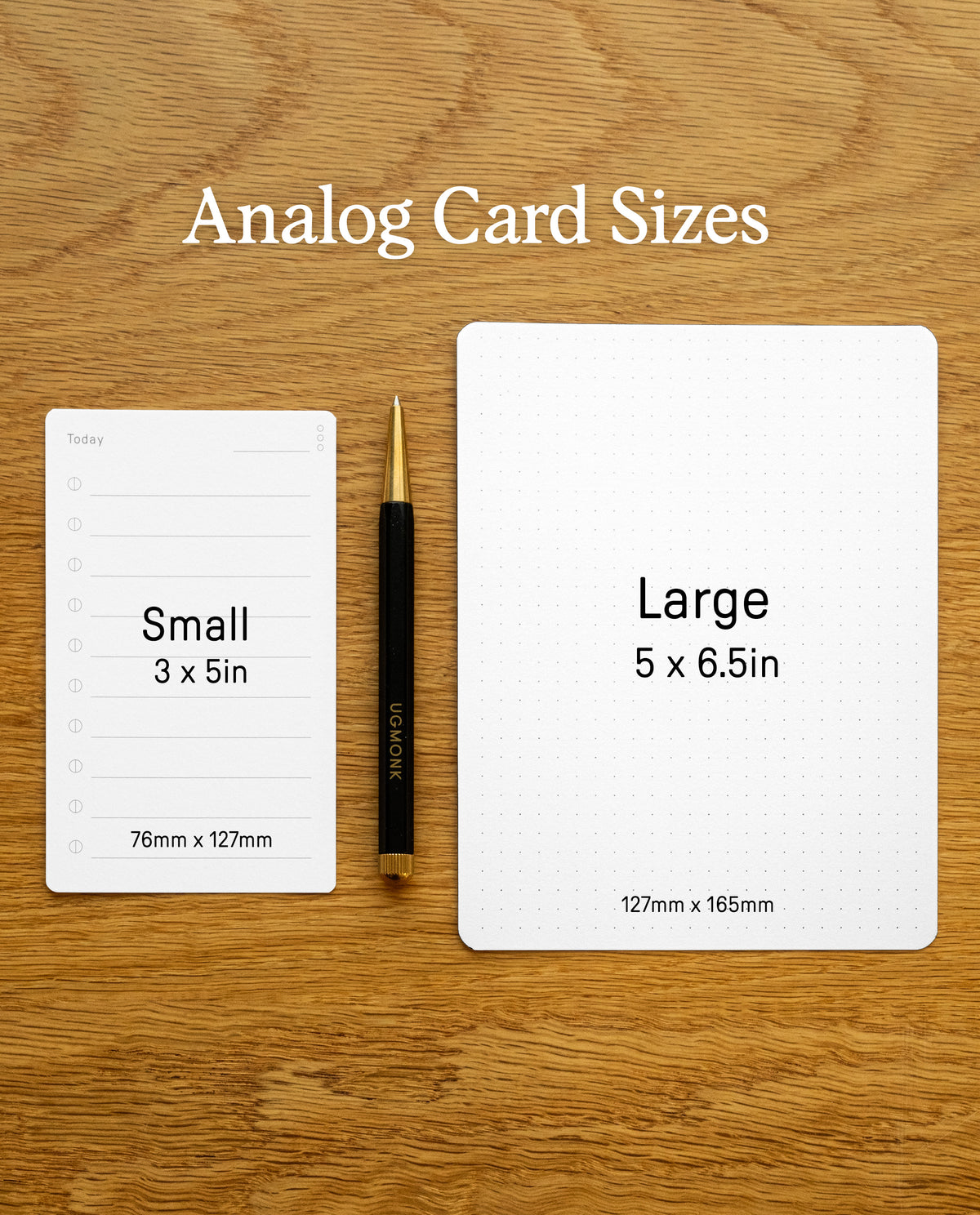 Two Analog Blank Cards—one labeled “Small” (3x5 in, 76x127mm), crafted from sturdy 100lb card stock and proudly made in the USA, and one labeled “Large” (5x6.5 in, 127x165mm)—rest on a wood surface with a black and gold pen between them. Text above the cards reads: “Analog Card Sizes.”.