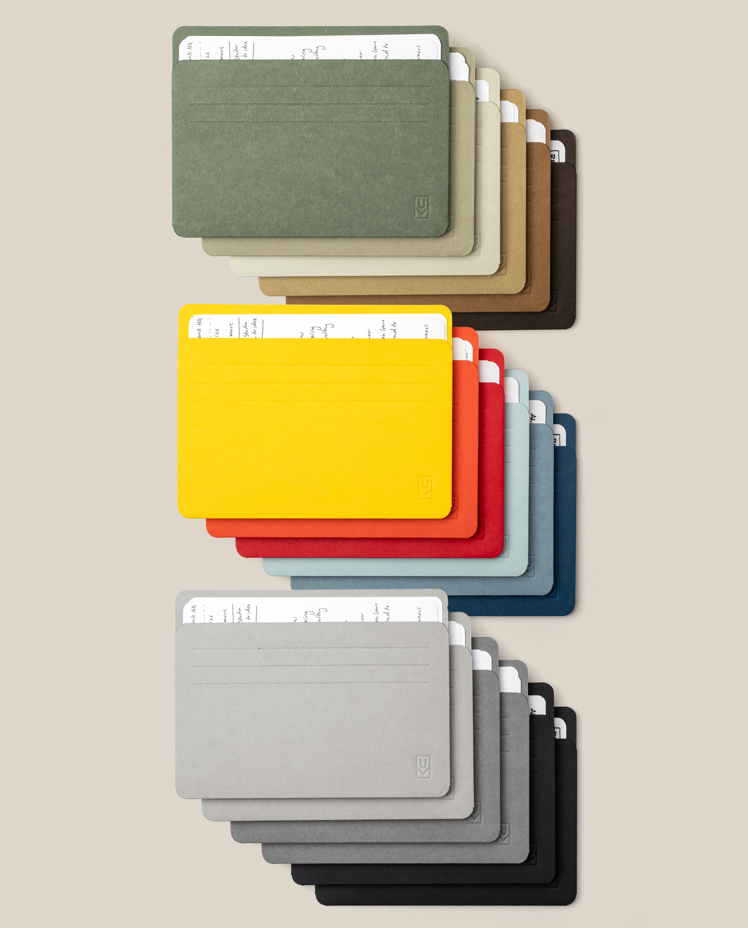 Eighteen Analog Card Sleeve Multipack - Large cardholders, each neatly securing two white cards inside protective Analog Card Sleeves, are arranged in three rows on a beige background. The top row showcases earth tones, the middle row displays vibrant colors, and the bottom row features grayscale shades—creating an organized and visually striking presentation of this stylish card organizer system.