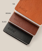Three Leather Discbound Analog notebooks in tan, brown, and black with full-grain leather covers are stacked diagonally on a beige background. Each has "Analog" embossed on the cover with color labels beside each notebook.