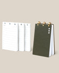 The Discbound Analog + 3 Refills, featuring a dark green cover, stands upright by three stacks of refillable task planner pages with brass disc binding, checkboxes, and lined note sections on a light beige background.