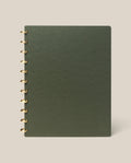 A large (8.5" x 11") Discbound Journal with a green plain cover and gold rings, refillable and spiral-bound, shown on a light beige background.