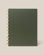 A large (8.5" x 11") Discbound Journal with a green plain cover and gold rings, refillable and spiral-bound, shown on a light beige background.