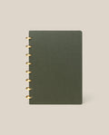 A Discbound Journal (Standard 6"x 8.5") in dark green with brass discs on the left stands upright against a plain beige background.