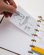 A hand lifts a notecard with pencil sketches and notes from a journal featuring dotted pages bound by the Discbound Punch system, with a visible to-do list on the right.