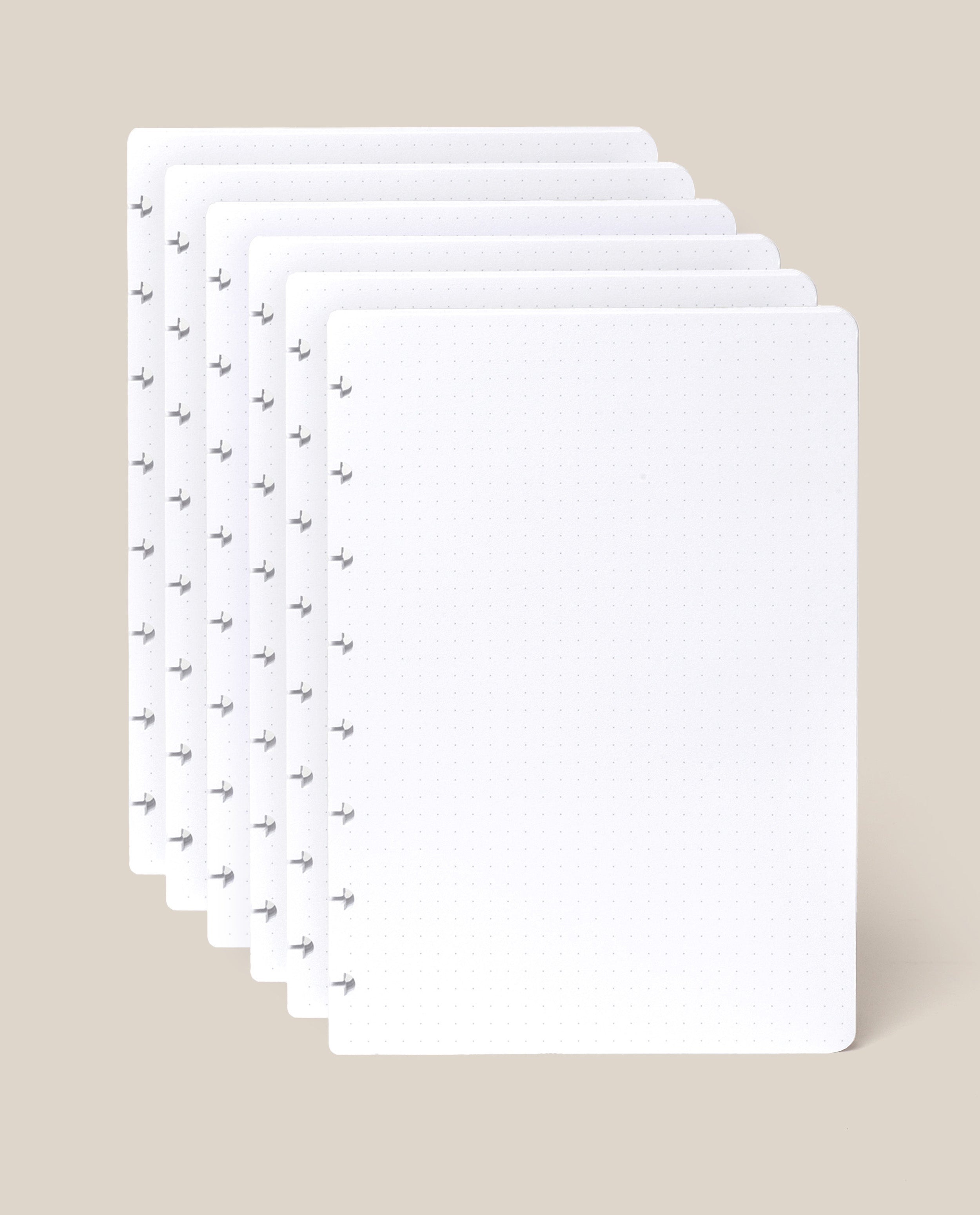 Six sheets of the Discbound Journal Refill - Dot Grid (Standard 6″ x 8.5″) with rounded corners are slightly fanned out against a light beige background, perfect for adding to your Heirloom Discbound Journal.