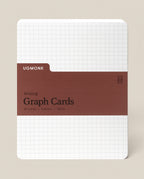 A pack of Analog Graph Cards - Large with a white grid background, brown label reading “Graph Cards, 50 Cards, 5x6.5in, 100lb,” and rounded corners. Made from sturdy uncoated cardstock for sketching, brainstorming, or note-taking.