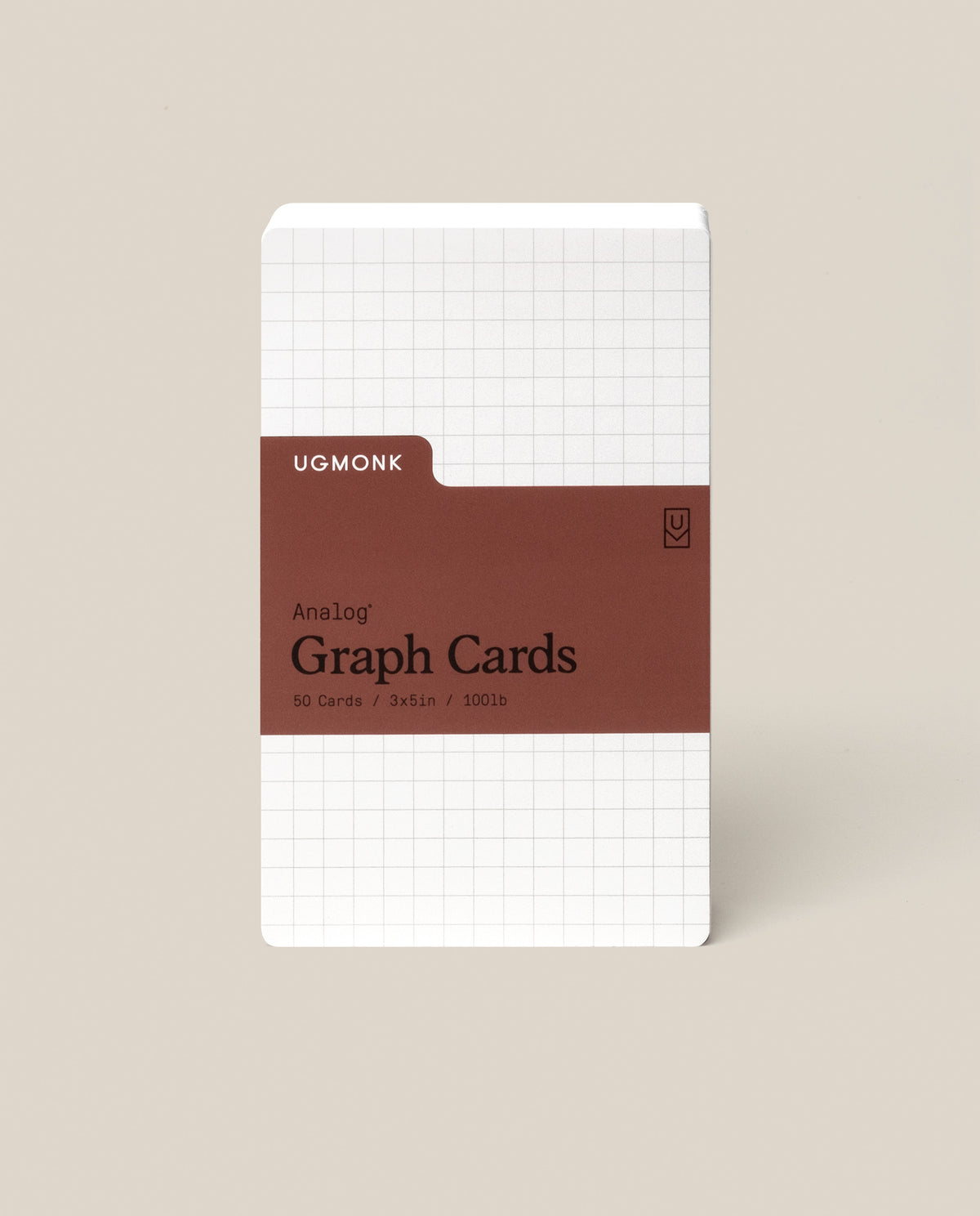 A pack of Analog Graph Cards - Small stands upright, made from uncoated cardstock with a white grid design and a brown label stating: Analog Graph Cards, 50 Cards, 3x5 in / 100 lb. The background is light beige.