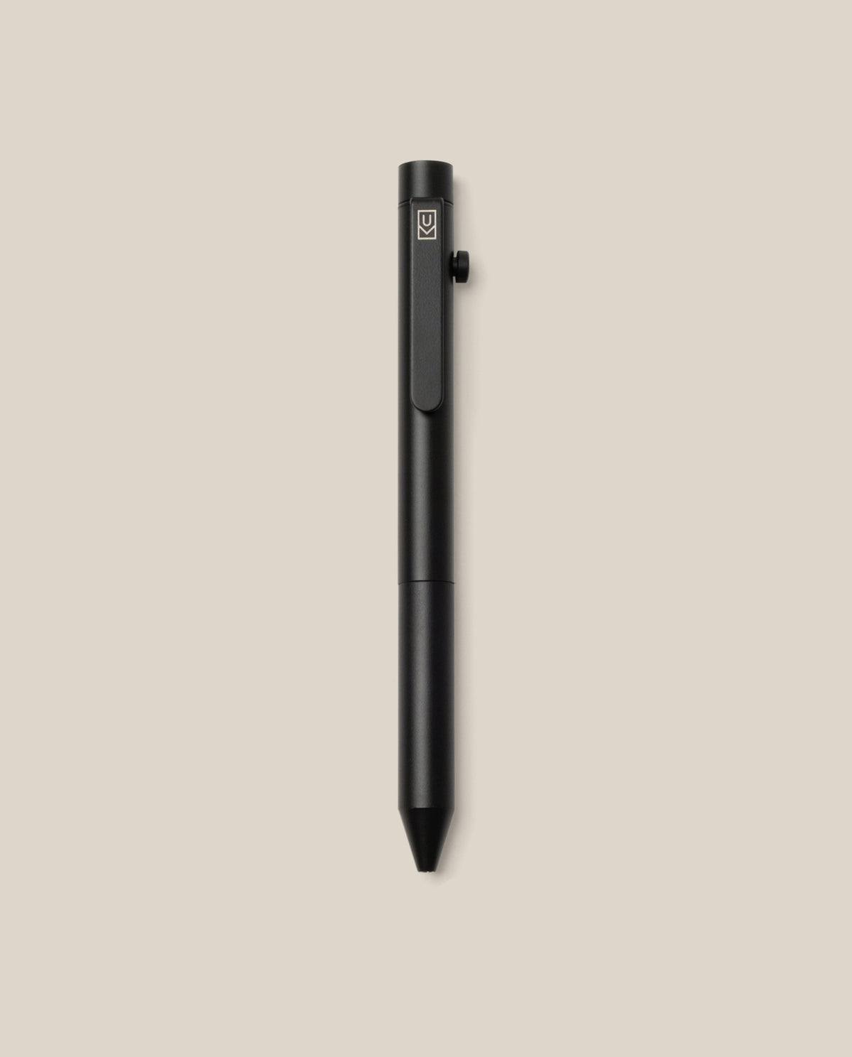 The INVENTERY Bolt Action Pen (Onyx), a sleek black writing instrument with a matte Cerakote ceramic coating, metal clip, and side button, is photographed standing upright against a plain beige background.