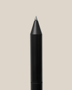 The INVENTERY Bolt Action Pen (Onyx) is displayed vertically with its pointed tip facing upward against a plain light beige background. Its sleek, black body is inspired by the classic Bolt Action Pen design and features a durable Cerakote ceramic coating for enhanced longevity and style.