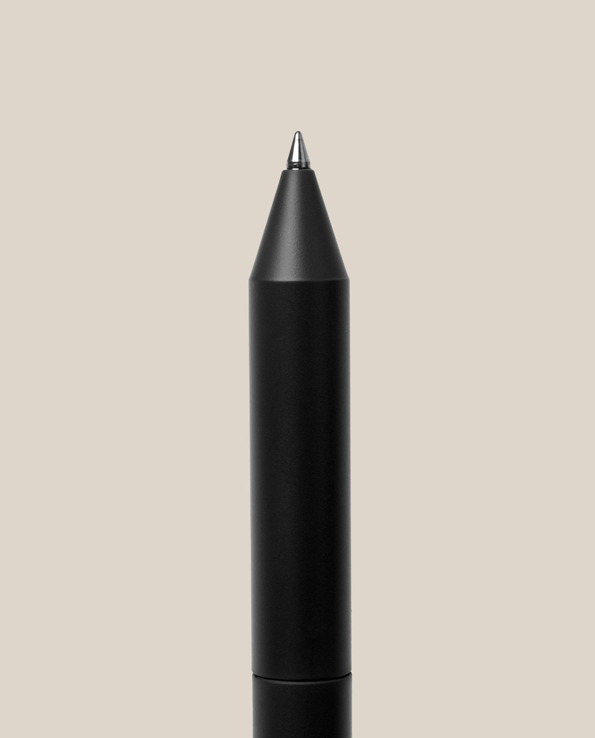 The INVENTERY Bolt Action Pen (Onyx) is displayed vertically with its pointed tip facing upward against a plain light beige background. Its sleek, black body is inspired by the classic Bolt Action Pen design and features a durable Cerakote ceramic coating for enhanced longevity and style.