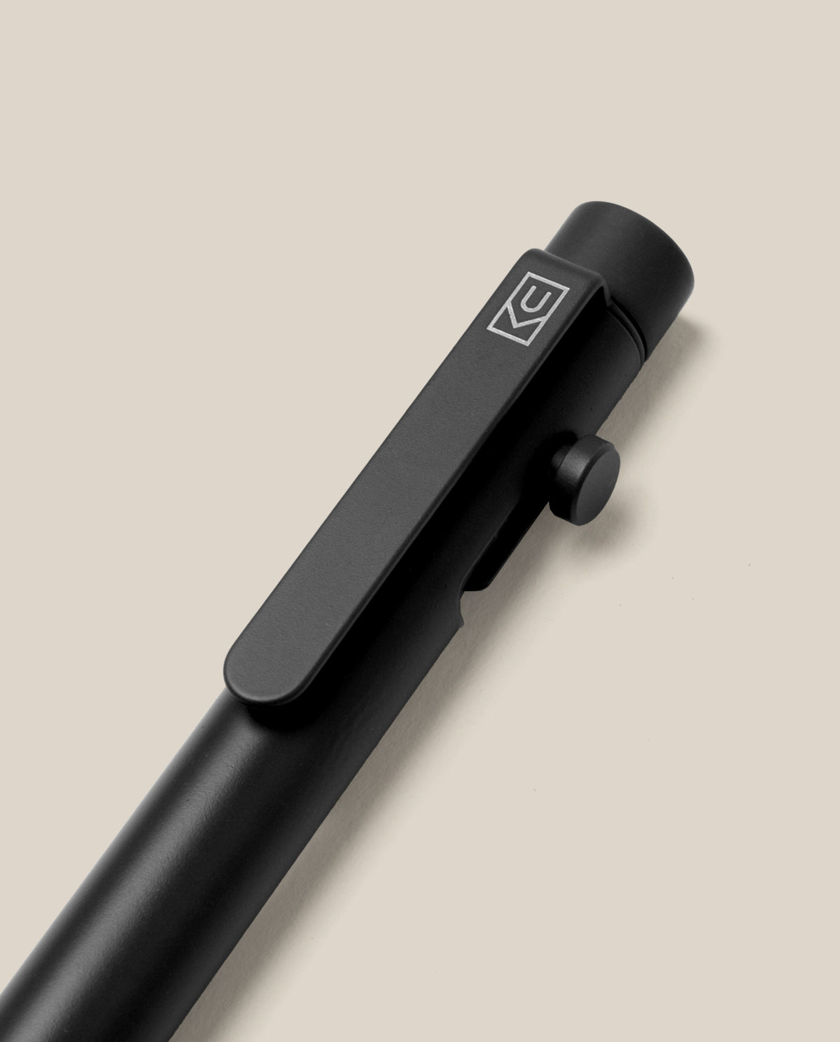 INVENTERY Bolt Action Pen (Onyx) with a matte black finish, clip, and a small knob near the top is displayed on a plain light beige background. The pen features a durable Cerakote ceramic coating, and its clip showcases a white geometric logo.