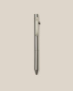 The INVENTERY Bolt Action Pen (Stainless), a sleek stainless steel ballpoint with a clip, is displayed vertically against a plain light beige background.