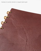 Close-up of the Warehouse Item - Discbound Heirloom Journal (Brown/Brass) featuring a full grain leather cover with brass discs, visible cosmetic blemishes, and unique irregular leather grain—ideal for a warehouse sale.