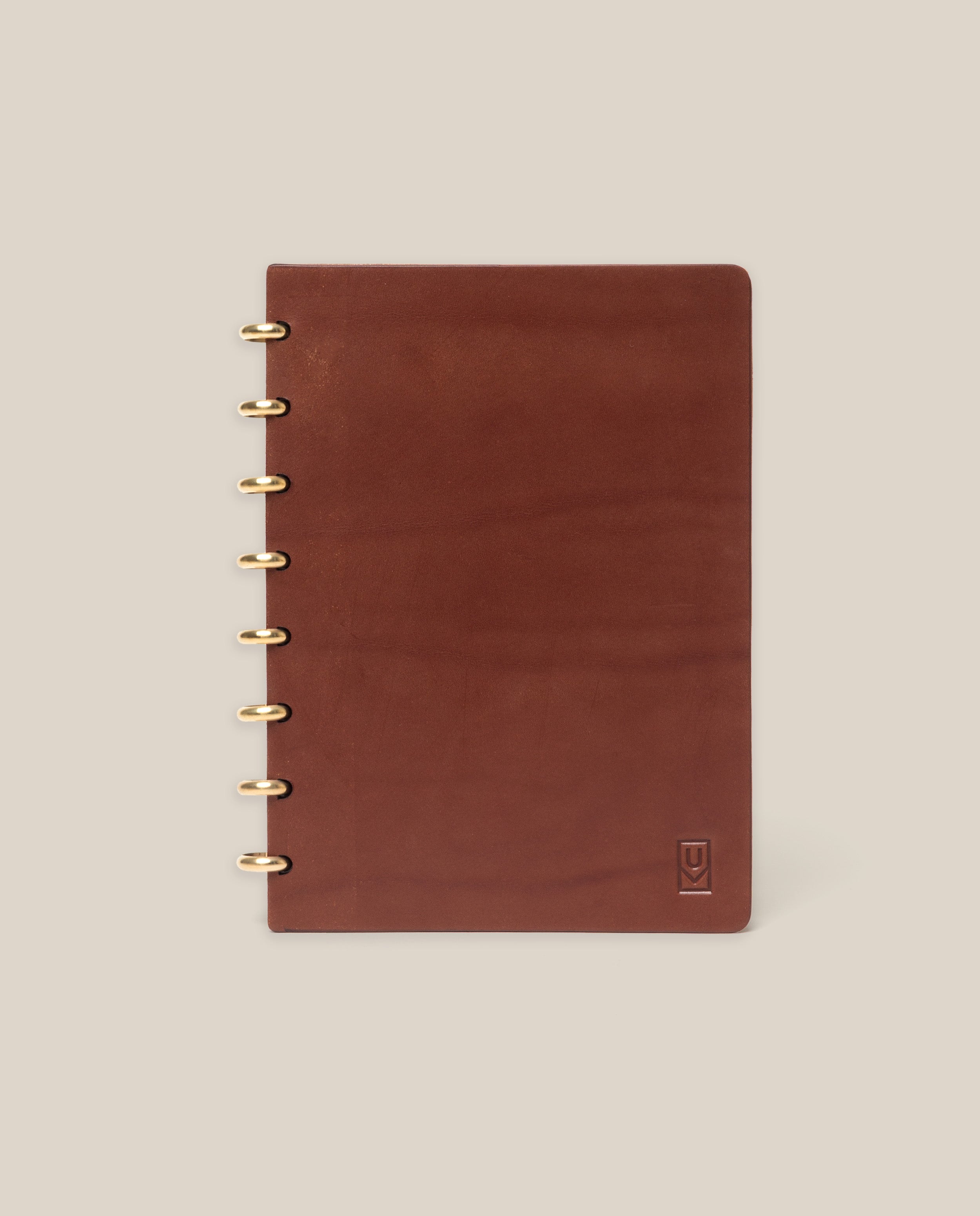 The Discbound Heirloom Journal (Brown Leather, 6" x 8.5") features refillable pages, gold disc binding, and a subtle embossed logo in the bottom right corner, shown on a plain beige background.