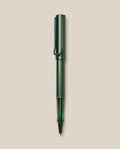A LAMY AL-star Rollerball (Pine) pen in green metallic, with matching cap and clip, is displayed vertically on a plain light beige background. This refillable pen ensures smooth, effortless writing.
