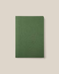 The Layflat Notebook (Green), featuring a geometric embossed design on its cover, rounded corners, and a green dot grid layout, is centered on a light beige background.