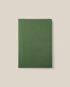 The Layflat Notebook (Green), featuring a geometric embossed design on its cover, rounded corners, and a green dot grid layout, is centered on a light beige background.