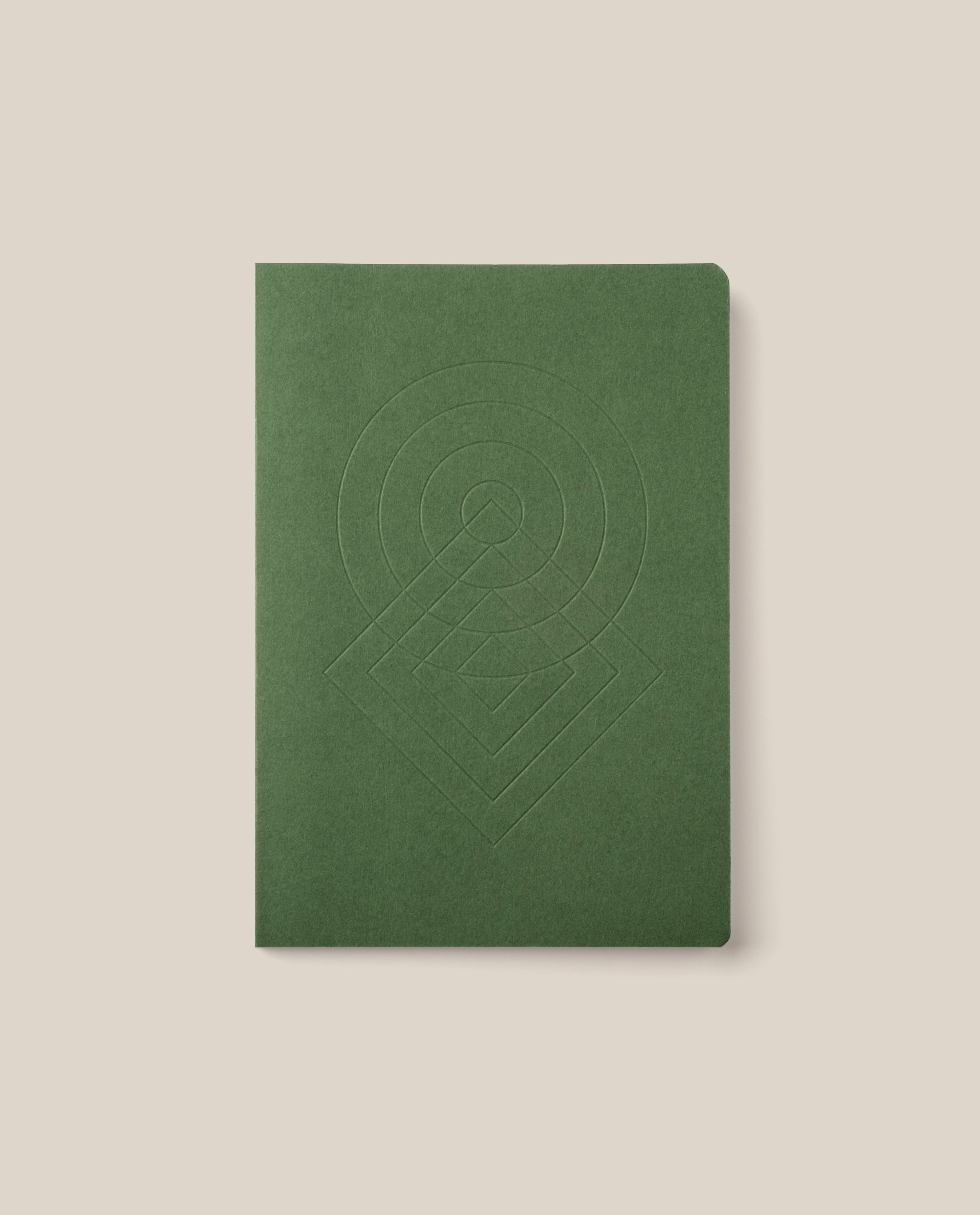 The Layflat Notebook (Green), featuring a geometric embossed design on its cover, rounded corners, and a green dot grid layout, is centered on a light beige background.