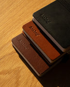 A Leather Discbound Analog + 3 Refills (Tan) notebook with a full-grain leather cover rests on a wooden surface, sunlight casting soft shadows across the scene.