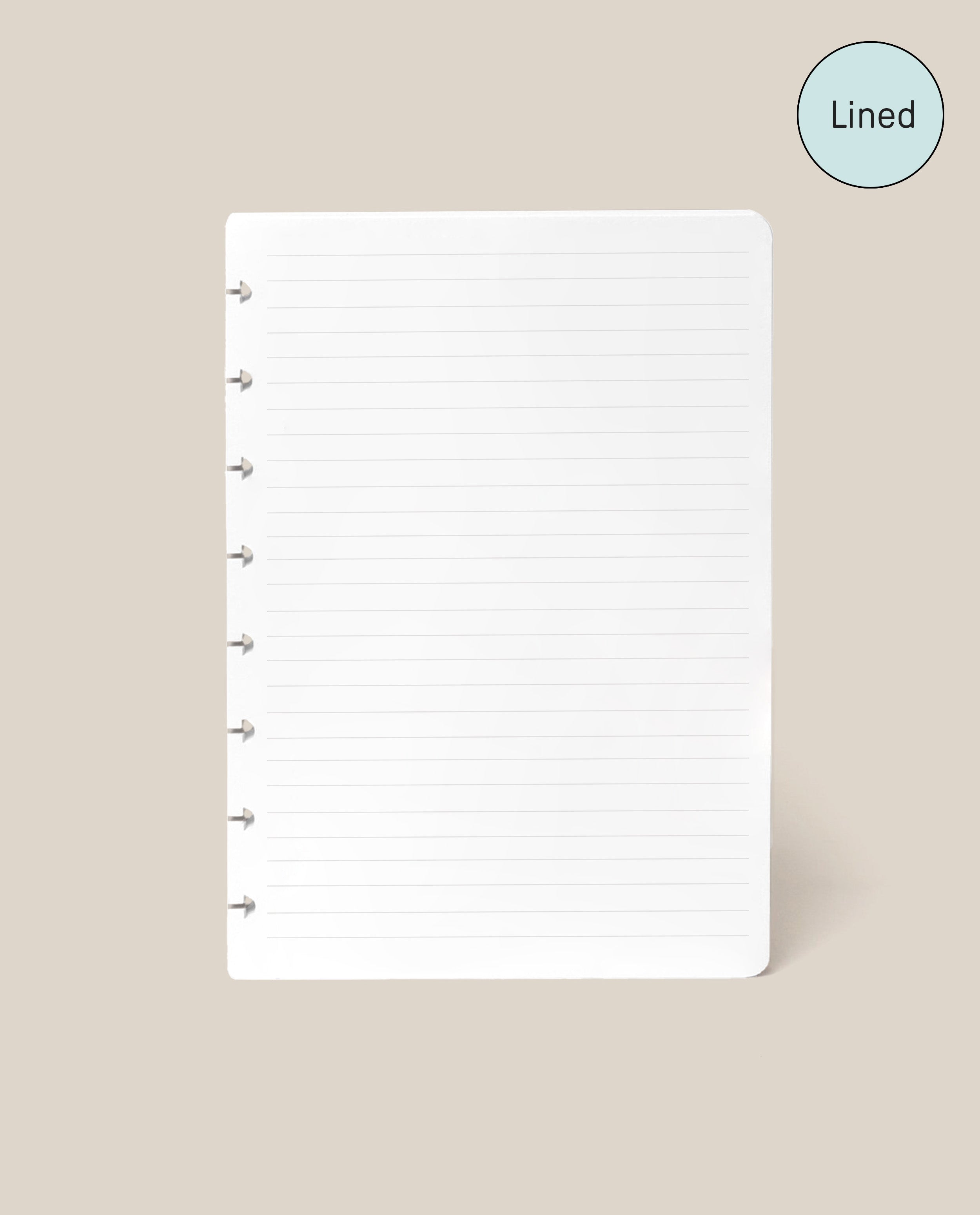 A Discbound Journal Refill - Lined (Standard 6″ x 8.5″) page, featuring white paper with disc-bound holes along the left edge and neat lines, is centered on a beige background. Designed as refill paper for your Heirloom Discbound Journal, each page includes a blue circle in the top right corner labeled “Lined.”.