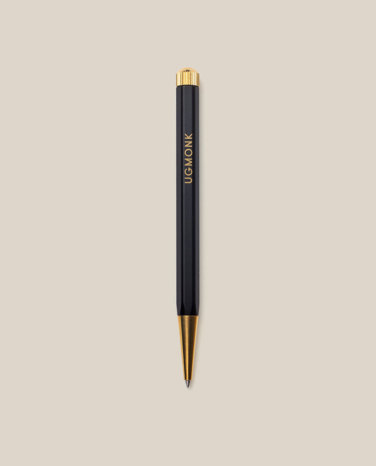 A Ugmonk Pen (Leuchtturm1917 Drehgriffel - Black) with gold accents and UGMONK in gold lettering on the barrel, shown against a plain beige background.