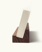 An Analog Weekly Card Holder (Walnut), handcrafted in Pennsylvania, stands upright with a closed book leaning on it. The natural walnut grain and the book’s pages are clearly visible against a plain white background.