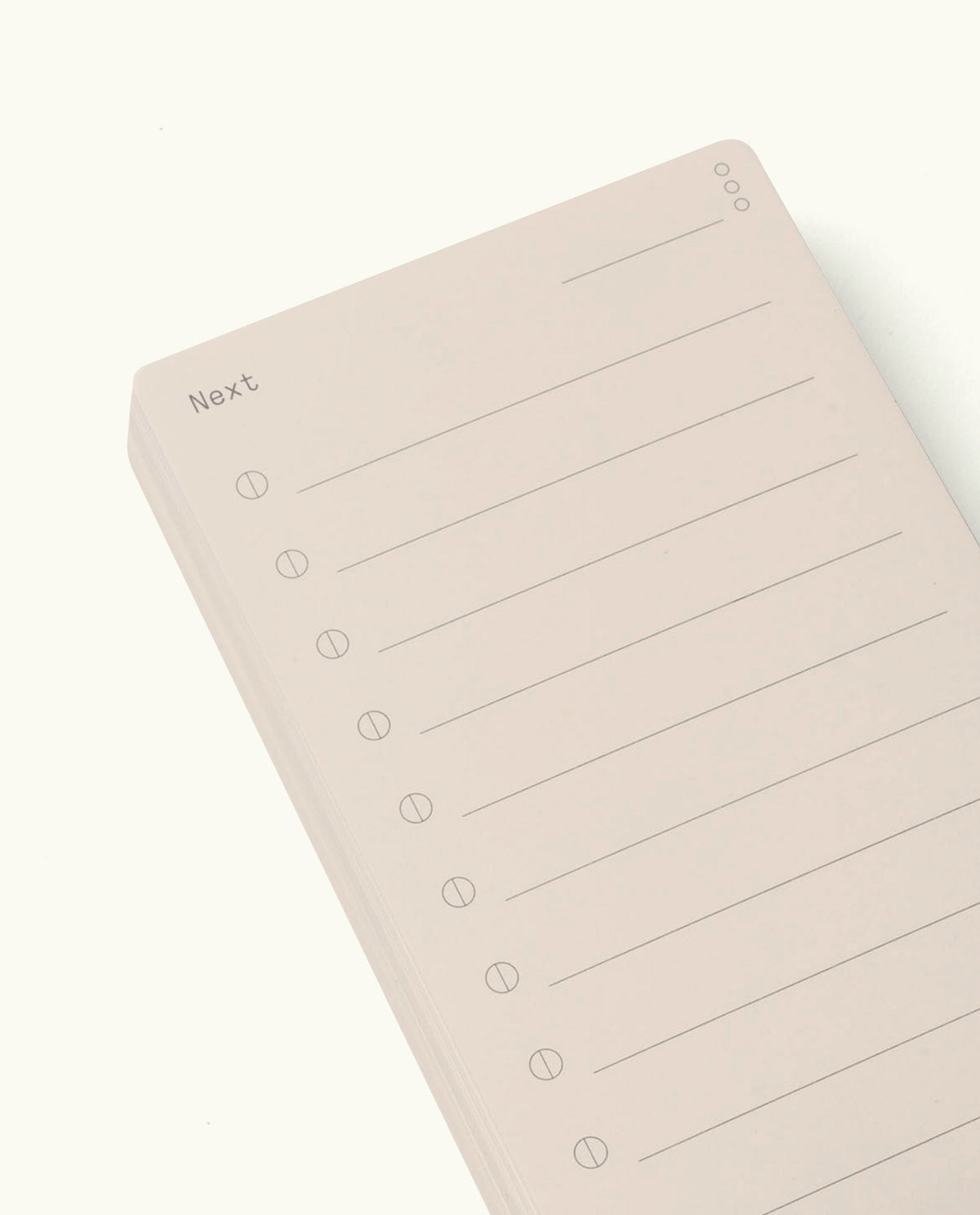 Analog - Next Cards are minimalist notepads inspired by analog design, featuring the word “Next” at the top left, ten blank lines each with a circle for easy tracking, and three small circles stacked at the top right. The notepad comes in a light beige color and is photographed against a white background. Ideal for goal setting and organizing your thoughts with clarity.