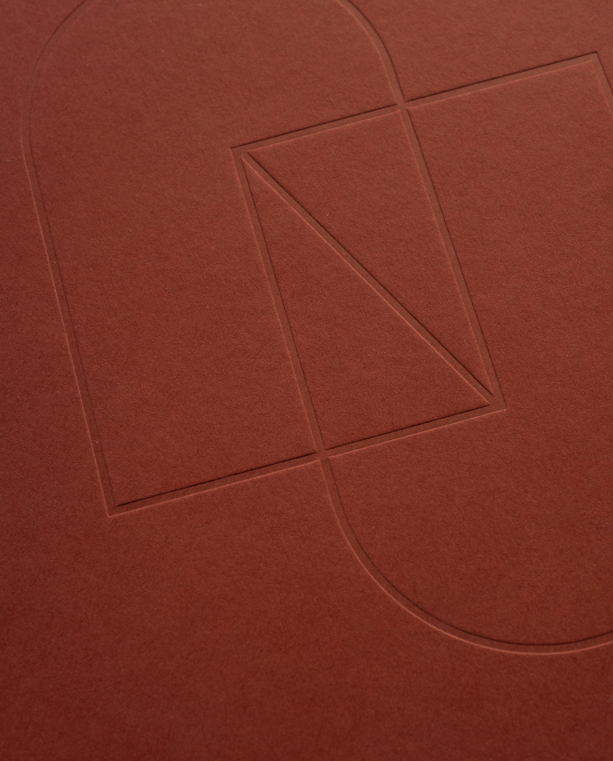 Embossed geometric shapes—a rectangle, triangle, and two semicircles—are outlined on the textured cover of the maroon Layflat Notebook.