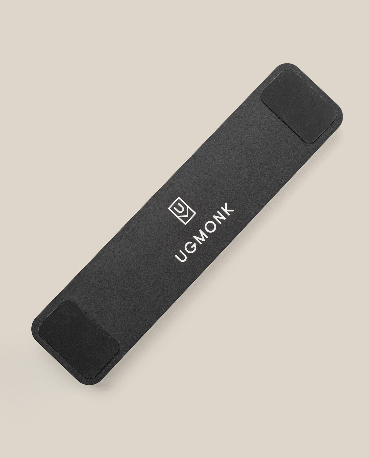 The Analog Pen Tray (Black Aluminum) is a sleek, rectangular aluminum organizer with rounded corners, black pads on both ends, and features the Ugmonk logo and text in white. It rests on a light beige surface.