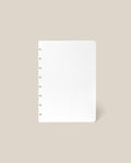 A Discbound Journal Refill - Dot Grid (Standard 6″ x 8.5″) with blank dotted pages and rounded corners is centered on a light beige background, making it the perfect dot grid refill paper for your Heirloom Discbound Journal.