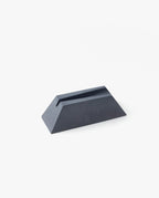 The Craighill Desk Knife Plinth (Slate) is a black, wedge-shaped cast concrete knife holder with a narrow slot on top, shown on a white background.