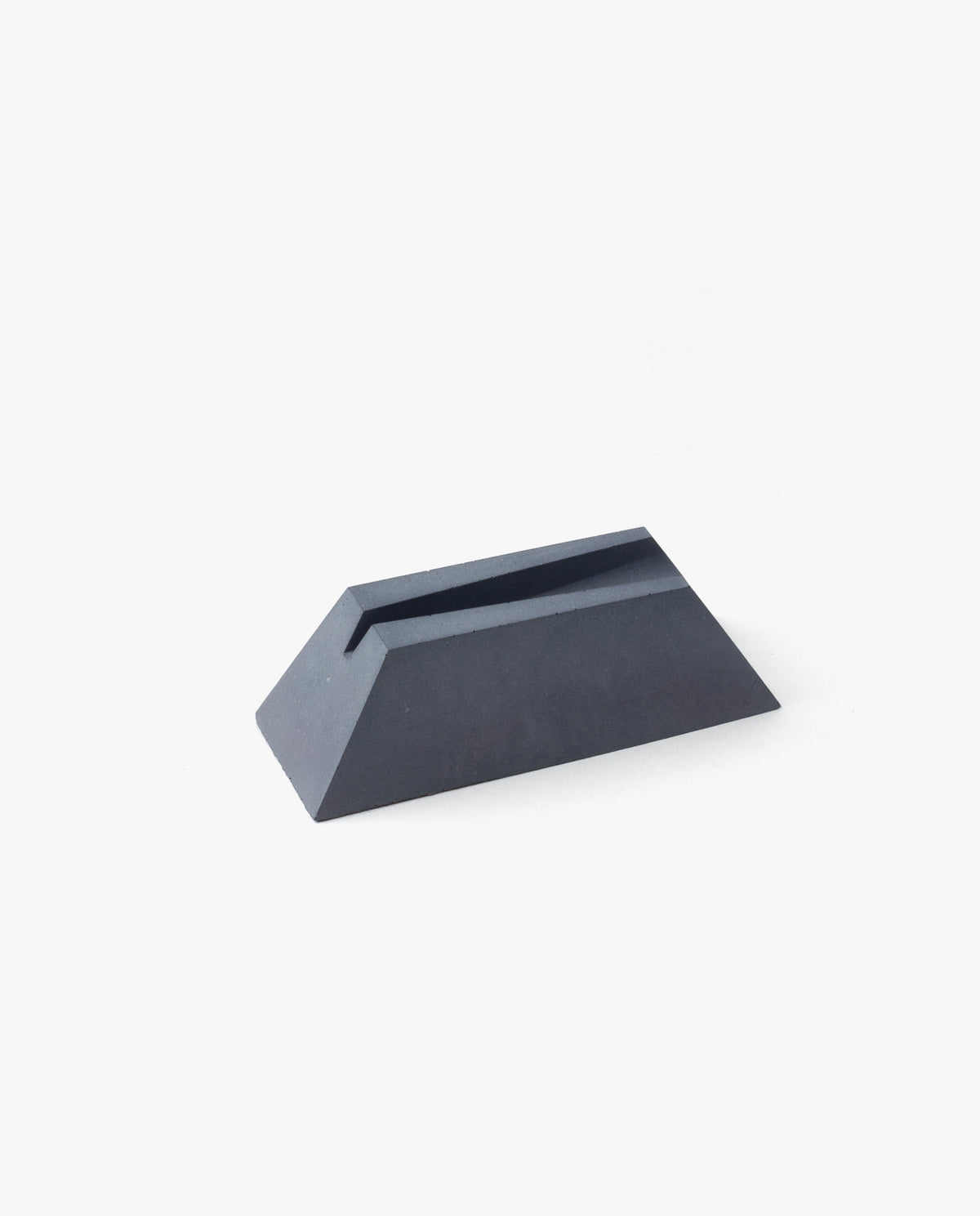 The Craighill Desk Knife Plinth (Slate) is a black, wedge-shaped cast concrete knife holder with a narrow slot on top, shown on a white background.